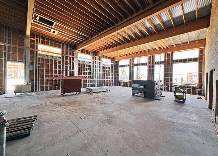 a large room under construction with metal framed walls and wood framed ceiling with piping